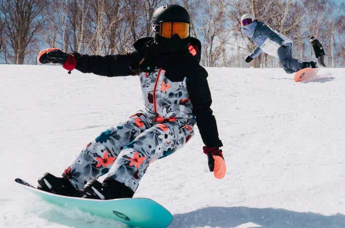 スノーボードウェアを着てゲレンデを滑る女性