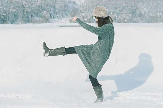 雪を蹴って遊ぶ防寒長靴を履いた女性
