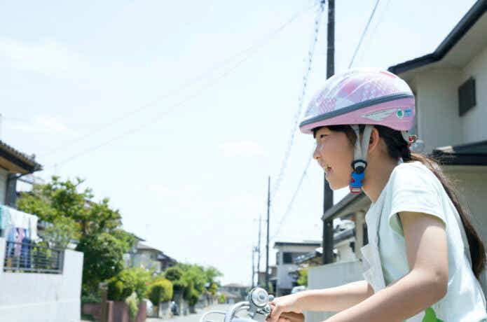 ヘルメットをかぶってジュニア向け自転車に乗る女の子