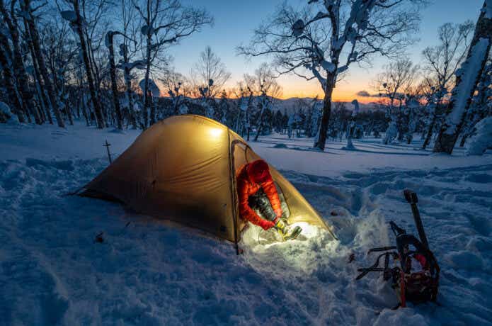 雪原で冬キャンプをしている人