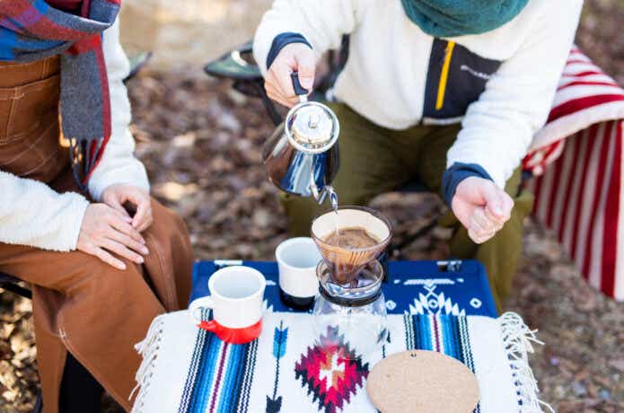 冬のキャンプでコーヒーを楽しんでいる2人の女性。