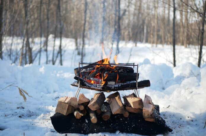 PIXTA_薪が燃えている雪中の焚き火台