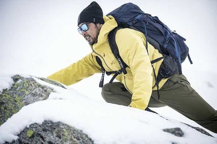 ハードシェルを着て雪山登山をしている男性。