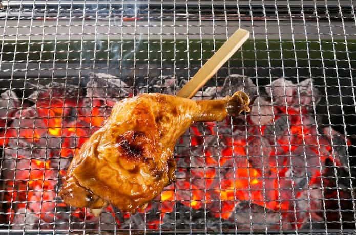 鶏ももの串焼きをバーベキューコンロで焼いている。