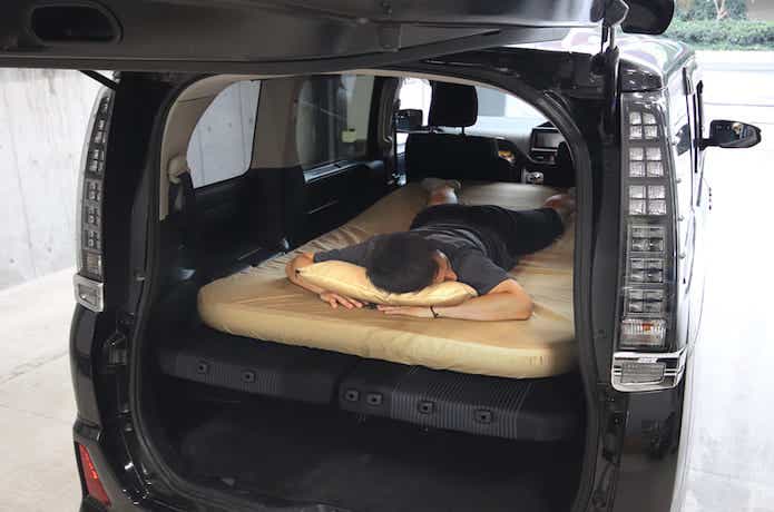 厚い車中泊マットに男性がうつ伏せの状態で寝ている