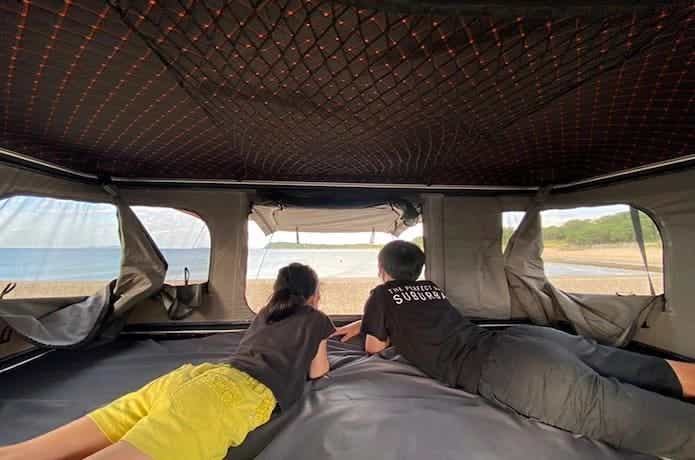 タワー型のルーフテントに寝そべっている2人の子供