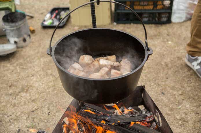 キャンプ場で鍋に入った肉を焼く