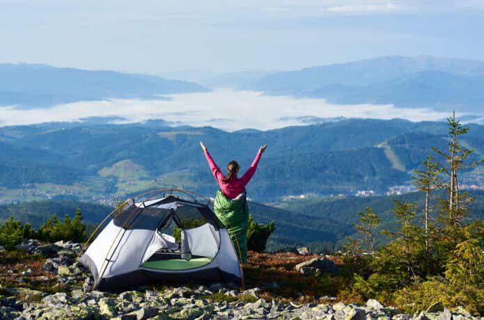 山にあるテントと腕を挙げる女性