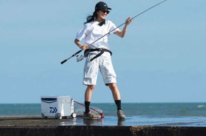 海で釣りをする女性と白いダイワのクーラーボックス    