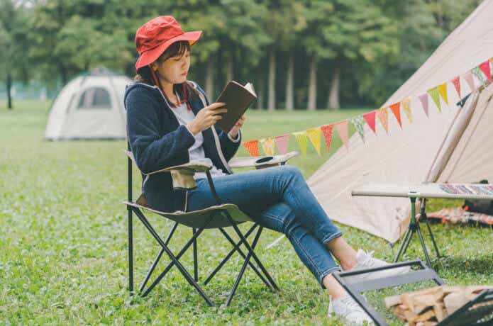 キャンプ椅子に座って読書をする女性