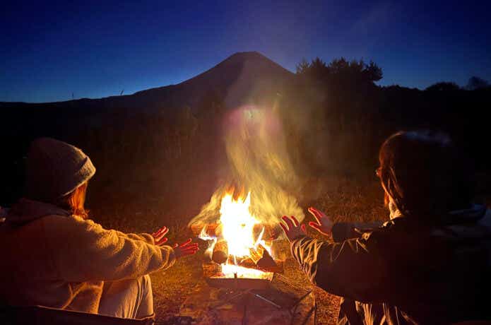 キャンプ場で焚き火で暖をとる男女