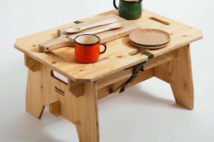 木製のアウトドアテーブルに食器を置く