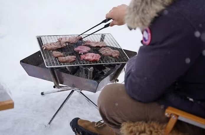 ユニフレームの「ファイアグリル」で肉を焼いている男性