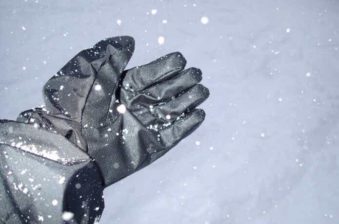 雪が降るなかでアウトドア用手袋を着用している