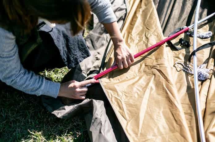 テントのポールを組み立てている女性