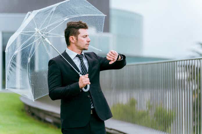 雨でビニール傘をさす外国人ビジネスマン