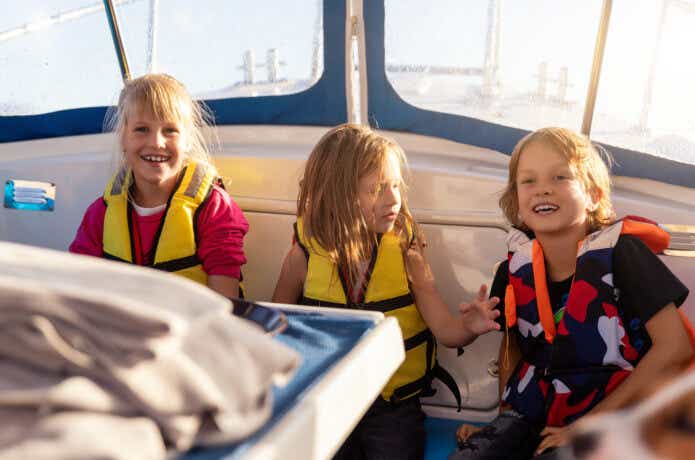 船にライフジャケットを着用して乗船している子供たち