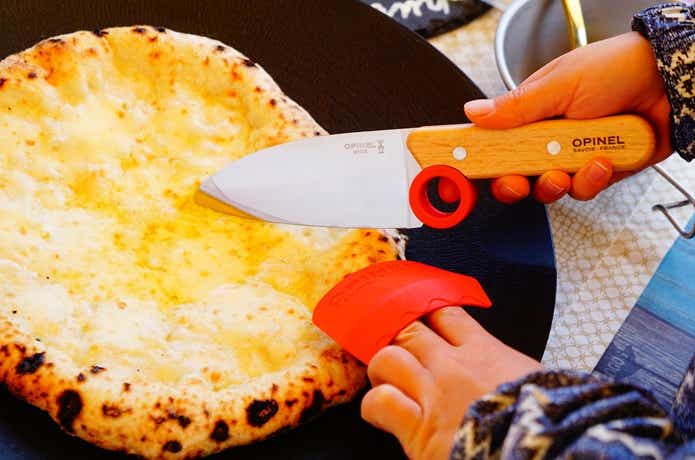 シェフナイフでピザを切り分ける子ども