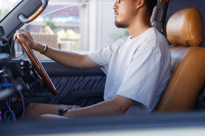 エルネストTシャツを着た男性が車を運転している