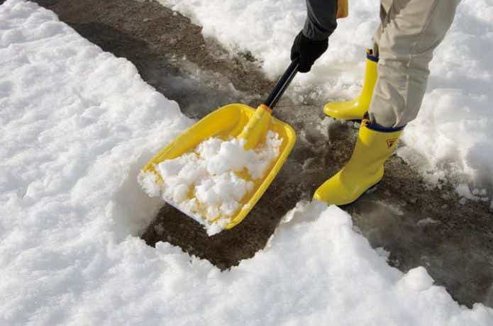 黄色のスノースコップで雪かき