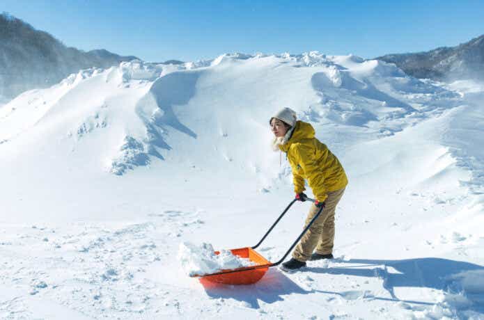 雪山でスノーダンプを使う女性