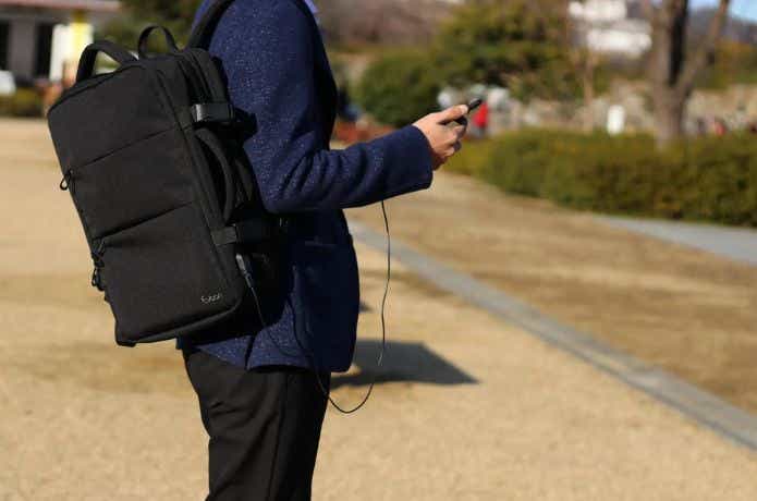 黒いビジネスバッグから充電コードを出してスマホを充電