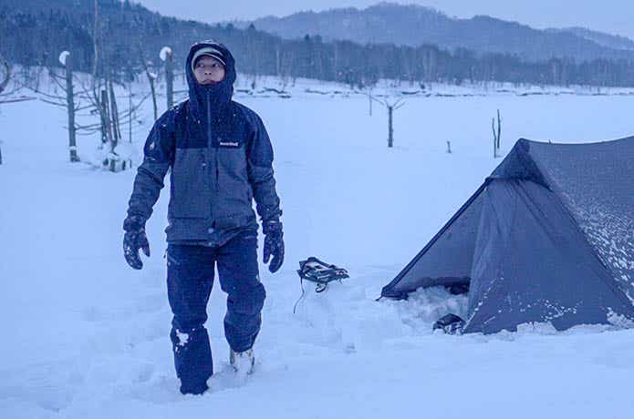 スノーウェアで雪中キャンプをする男性