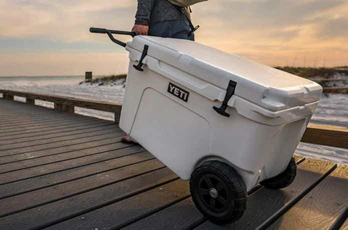 白いキャスター付きのクーラーボックスを引く人