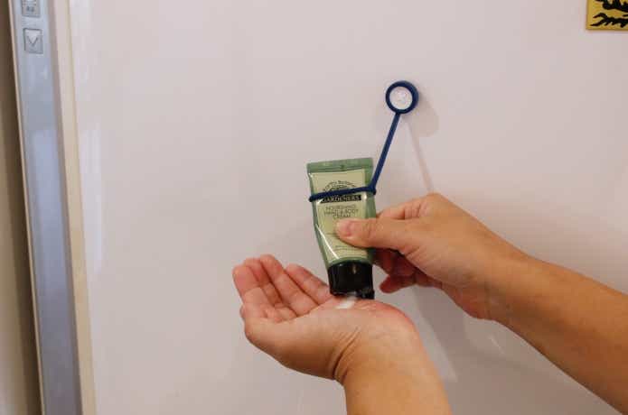 ボタンスリングでハンドクリームを冷蔵庫に貼り付けている