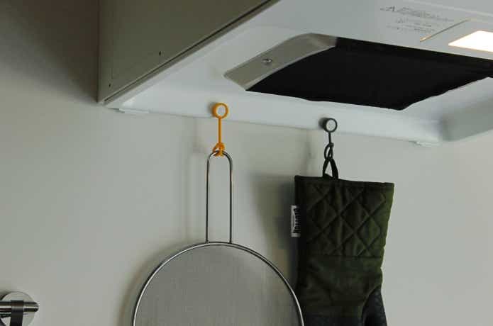 ボタンスリングでレンジフードに油はね防止ネットとミトンを吊っている