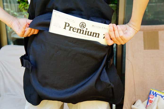 無印良品アウトドアエプロン背面ポケットに雑誌を入れいてる様子