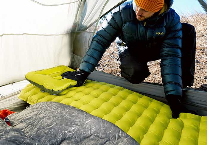 テント内にタイニースリーピングパッドを敷く男性