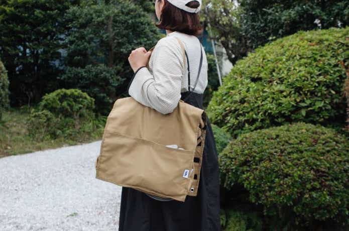 ユニットシステムベースMを半分に折りたたんで肩にかけている