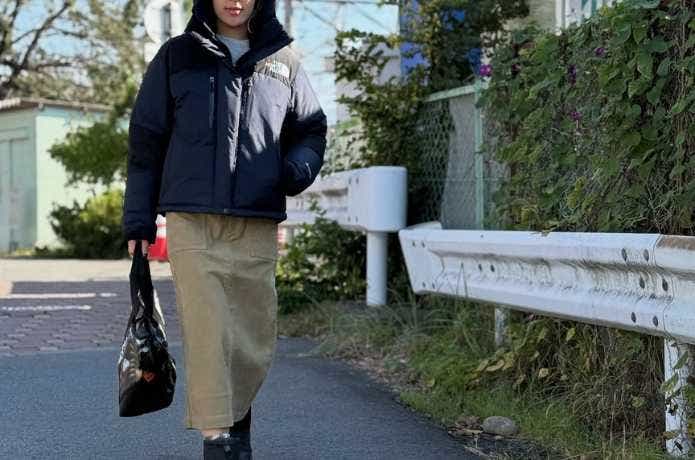 黒いザ・ノース・フェイスのダウンを着て歩く女性