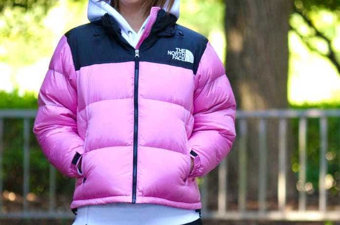 ピンクのザ・ノース・フェイスのダウンジャケットを着る人