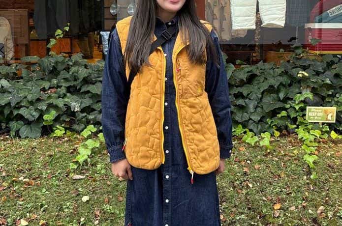 デニムのワンピースにオレンジのフリースベストを合わせたコーデ