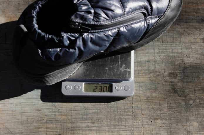 防寒パフィーシューズの重さを測っている