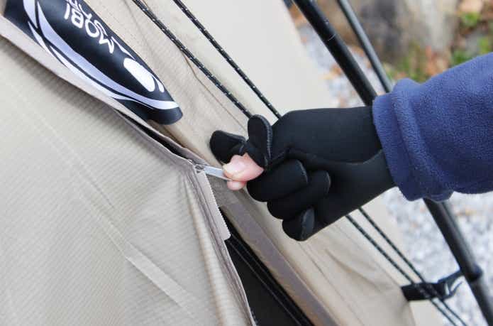 クリマプレンフィッシンググローブ着用でテントのファスナーをつまんでいる