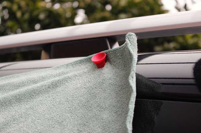 マグネット入り吸盤2つを使ってクルマの窓にタオルを貼り付けてある