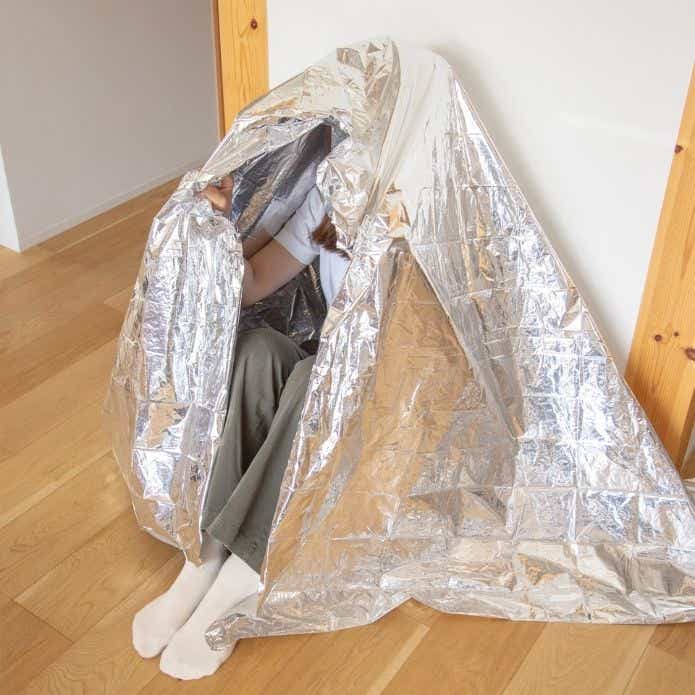 無印良品 エマージェンシーシート（いつものもしも）に包まる人