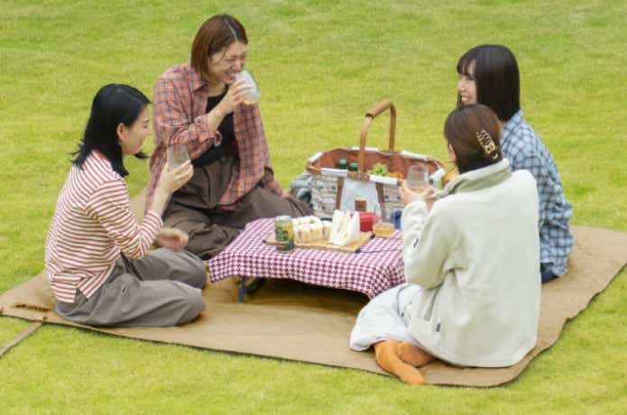 ロゴス「風にも負けないレジャーシート」に座る女性