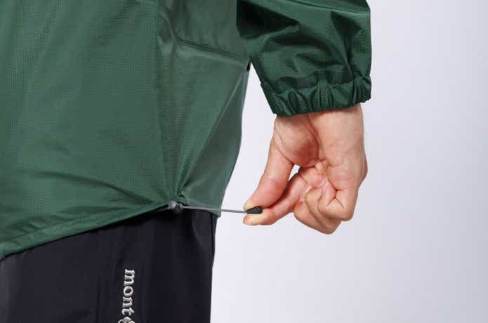 モンベル「レイントレッカー ジャケット Men's」の裾を絞る男性