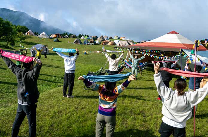 屋外でてぬぐいを持って背中を伸ばしている人