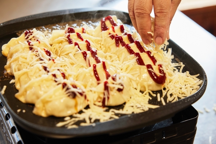 餃子にチーズ、コチュジャンをトッピングしている写真