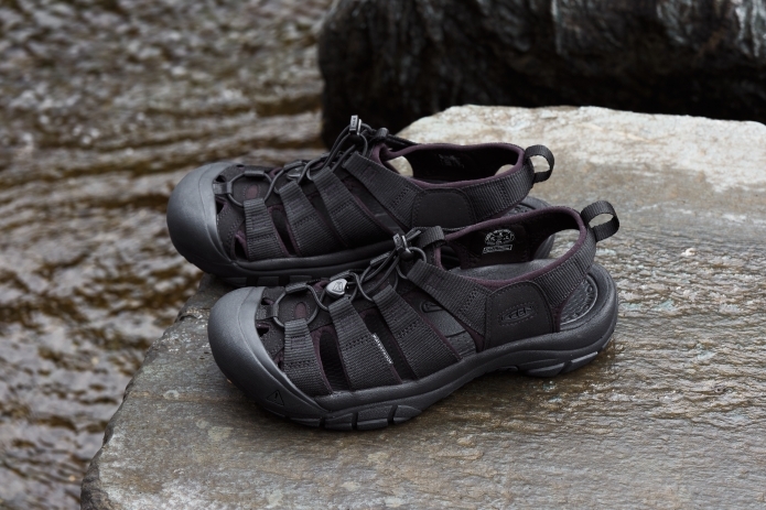 濡れた岩の上に置かれた黒いサンダル