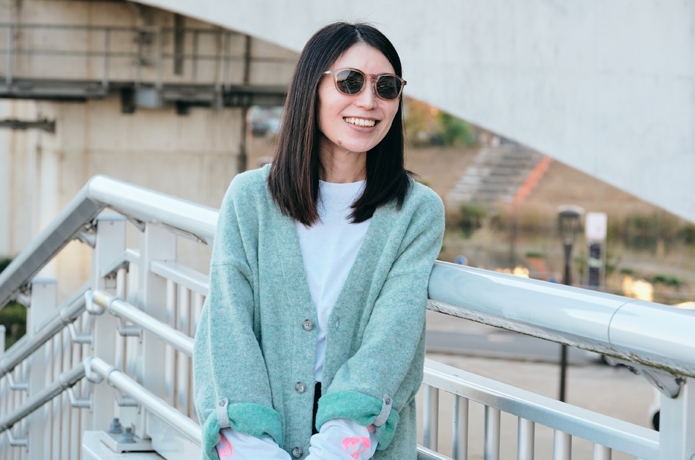 サングラスをかけ、橋の上で微笑む女性