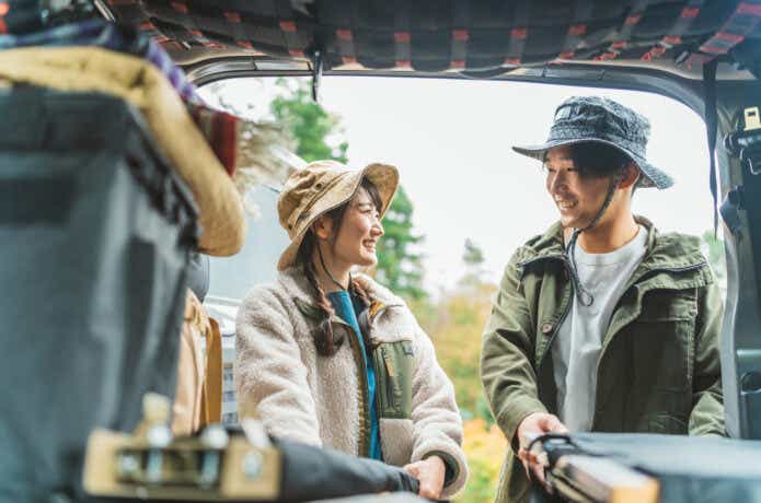 車のラゲッジで談笑するカップルの写真