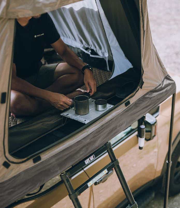 スノーピーク「フィールドライズ」での前室で飲み物を飲む人