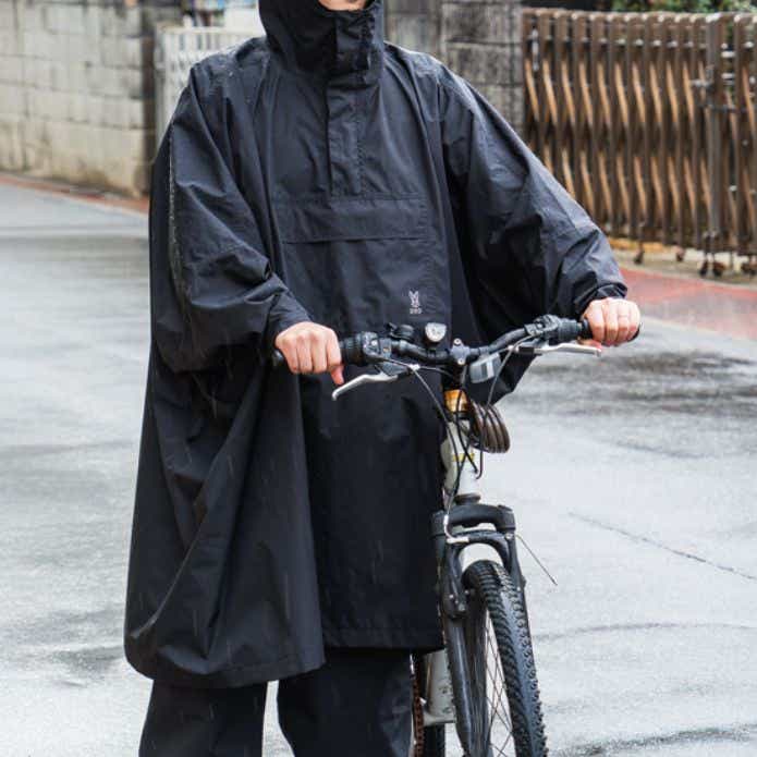 DOD「カッパーダ・ポンチョ」を着て自転車を押す男性