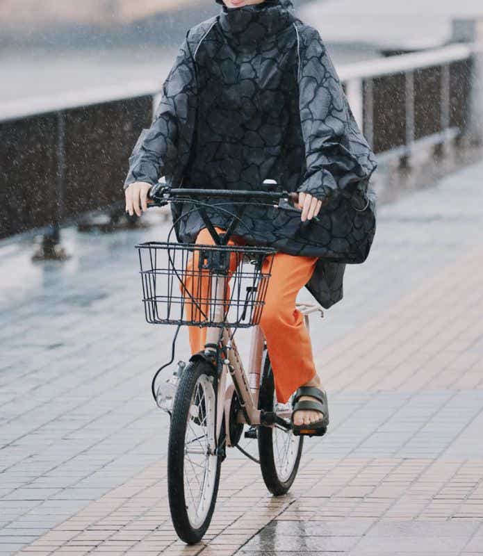 レインポンチョを着て自転車に乗る女性